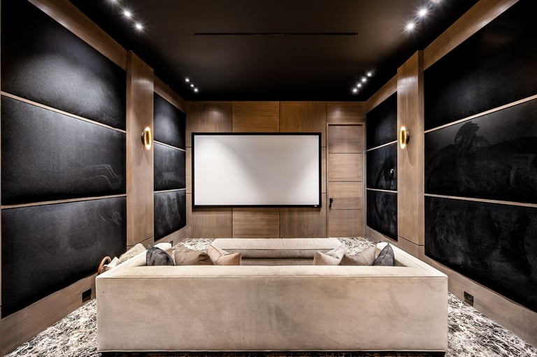 A modern home theater room with comfortable seating, a large screen, and elegant wood paneling and black acoustic walls