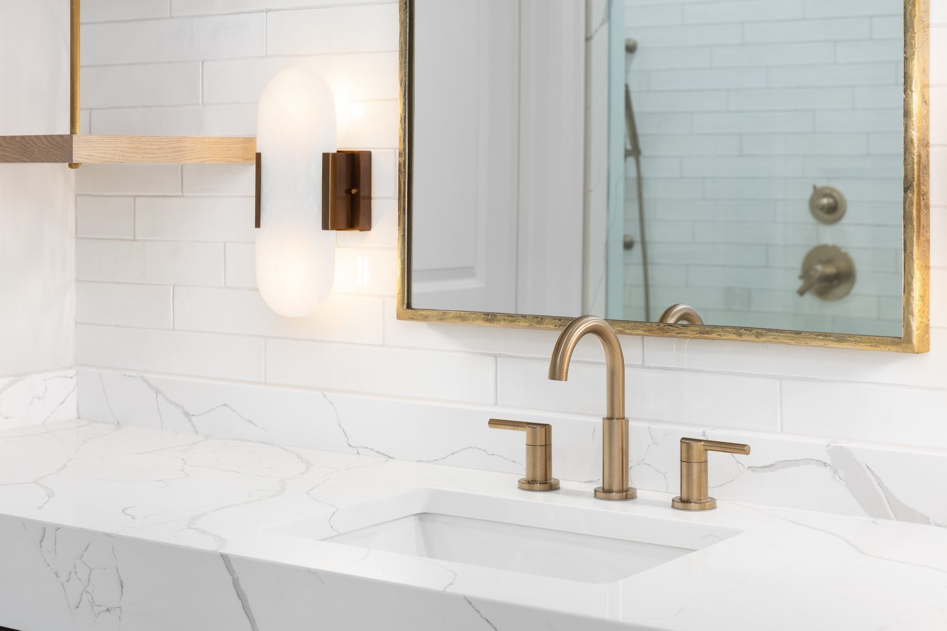 Modern bathroom with elegant tile work, marble countertop, and gold fixtures