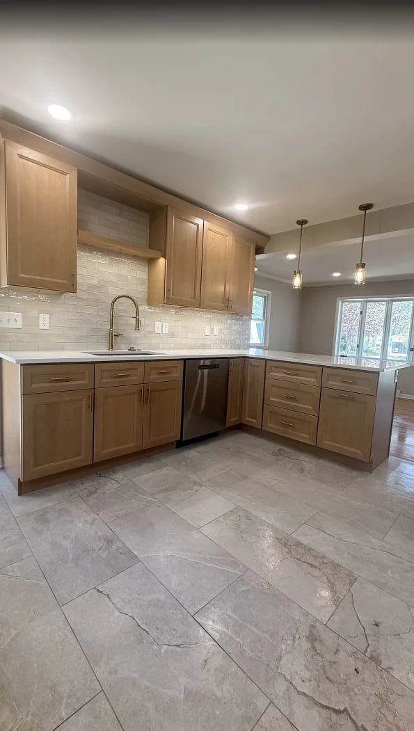 Modern kitchen with wooden cabinetry, white subway tile backsplash, stainless steel appliances, gray tile flooring, and pendant lighting