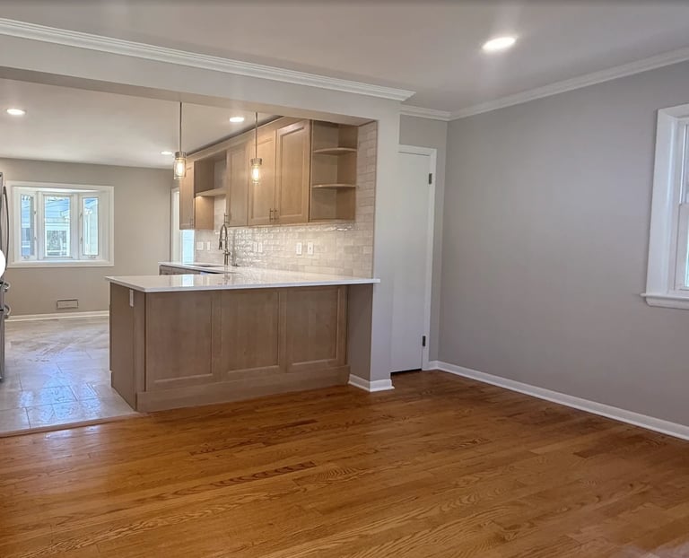 Modern kitchen with wooden cabinets and white marble backsplash overlooking hardwood living room space
