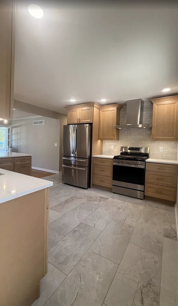 Modern kitchen with wood cabinets, stainless steel appliances, white island, gray tile flooring, and recessed lighting